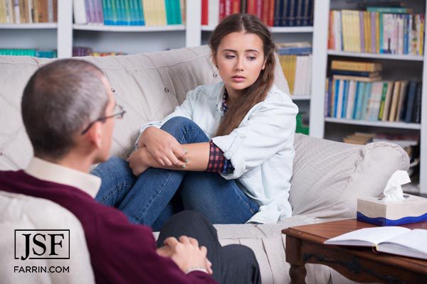 girl sits on a couch while talking to a mental health specialist