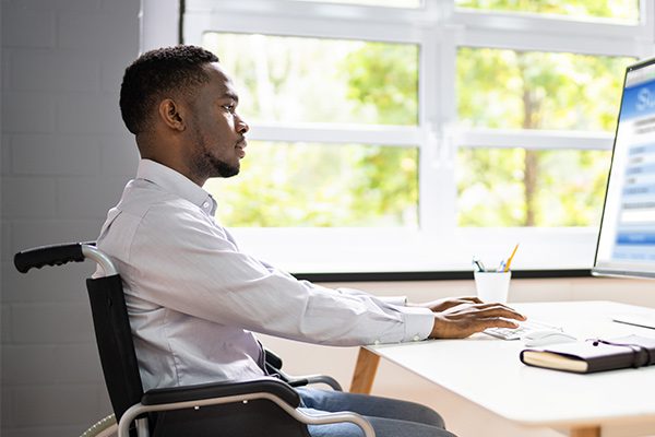 A man using a wheelchair fills out a Social Security Disability work credits form on a computer