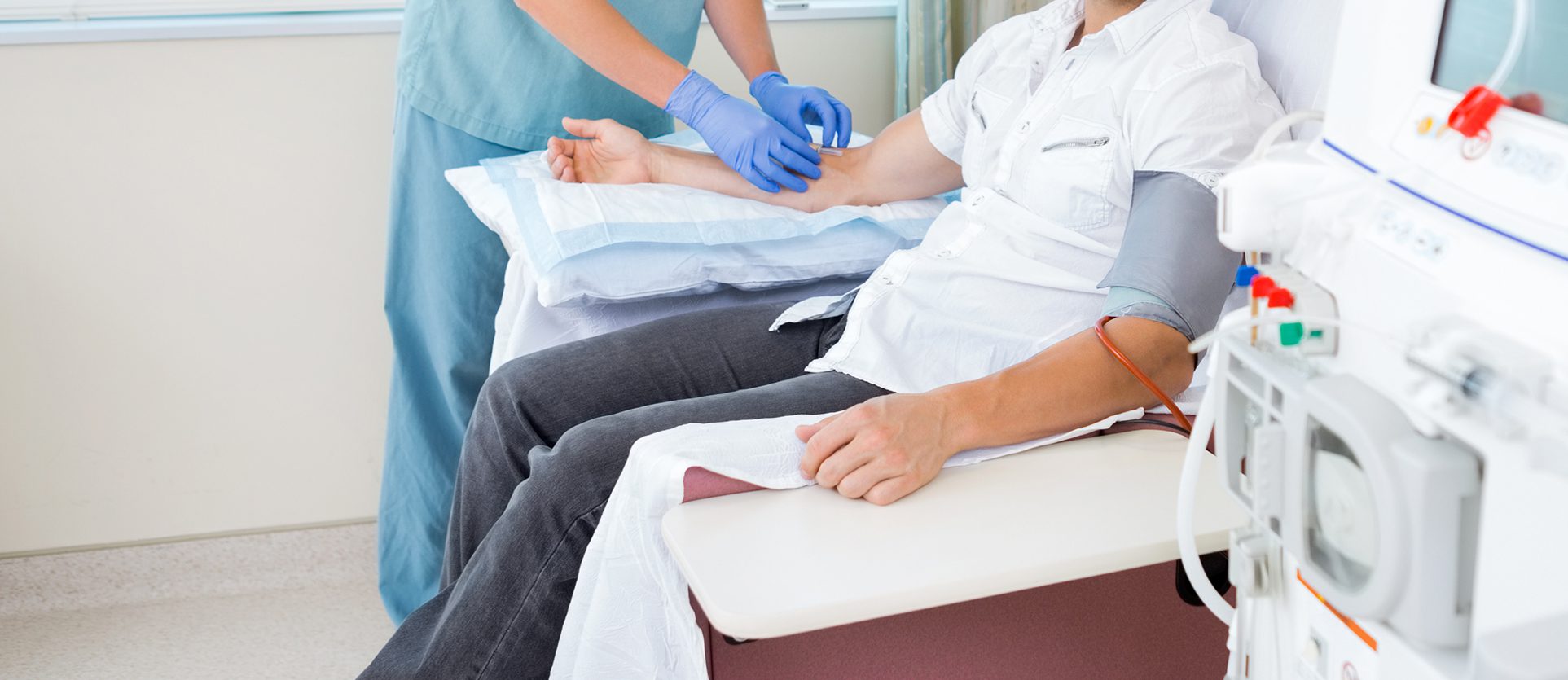 A man undergoing kidney dialysis with the help of a nurse.