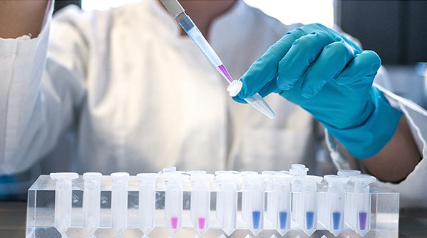 A researcher filling sample vials with a pipette in a lab.